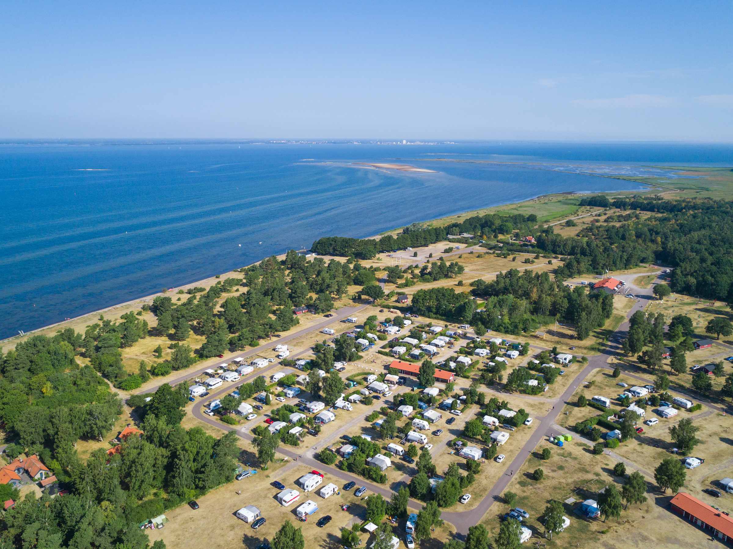 Flygbild över Haga Park med campingen bland träden, stranden och Kalmarsund